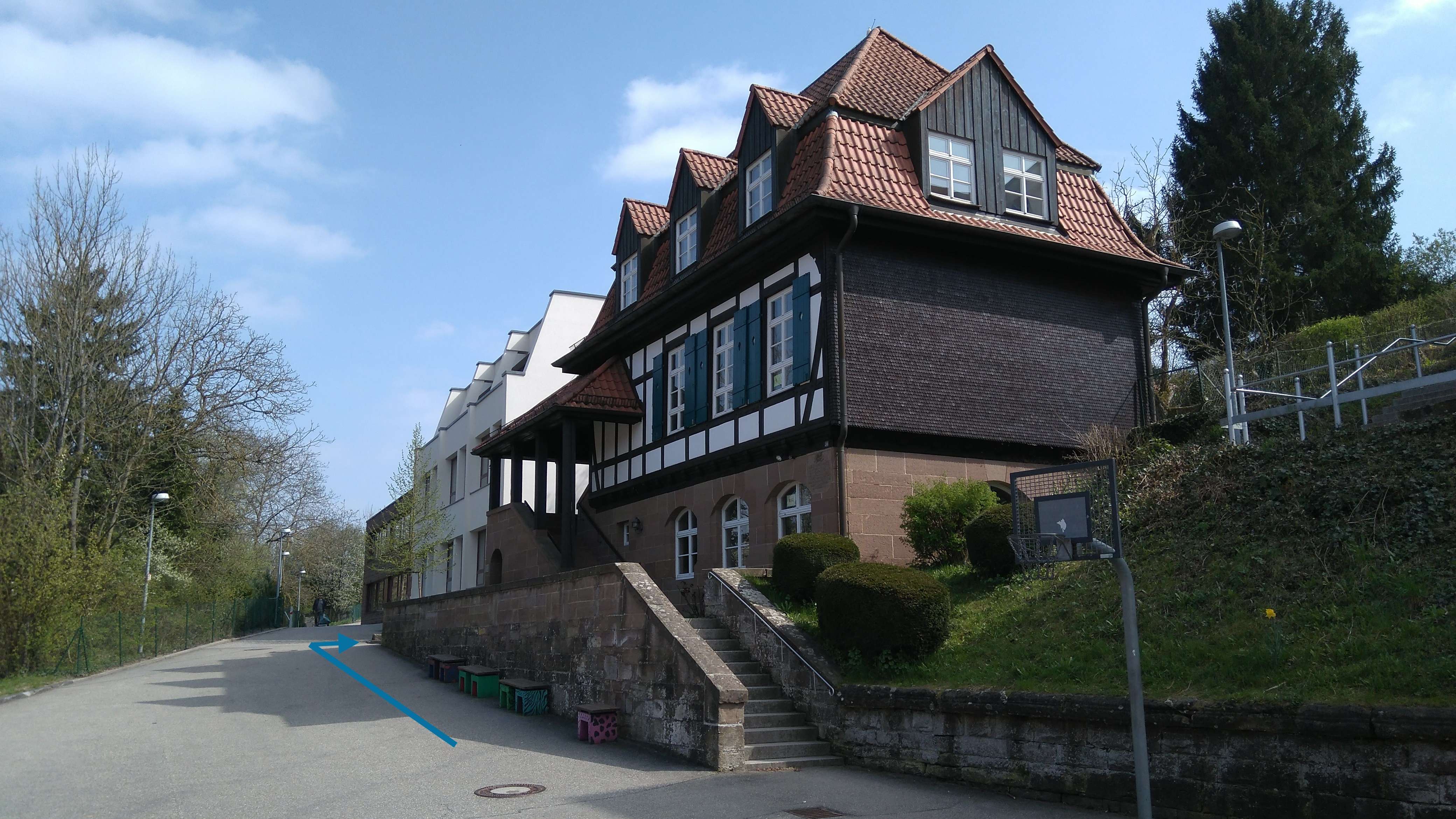  Links neben dem Karl-Klotz-Haus (Fachwerkhaus) befindet sich der Aufgang zum Hauptgebäude (blauer Pfeil auf Foto). Dort finden Sie das Sekretariat, die Verwaltung und das Lehrerzimmer. 